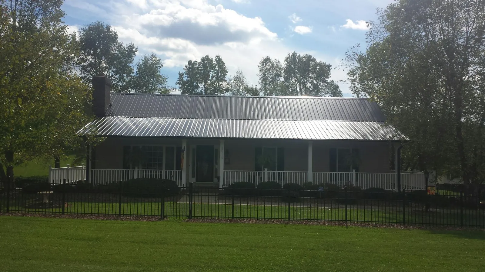 Gray metal roof on a brick ranch with a full width front porch — Gutter Guard Installation work by our crew in Woodward